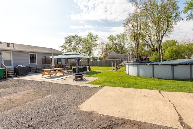view of yard with a fire pit, fence, a gazebo, a patio area, and a fenced in pool