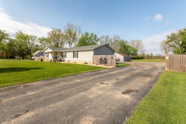 ranch-style home featuring a front lawn and fence