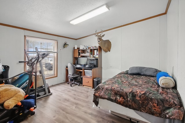 bedroom with light wood-style floors, ornamental molding, and a textured ceiling