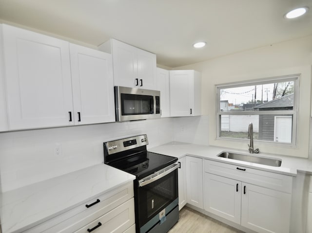 kitchen with stainless steel appliances, a sink, white cabinetry, tasteful backsplash, and recessed lighting