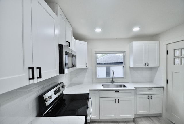kitchen with stainless steel appliances, a sink, white cabinetry, backsplash, and recessed lighting