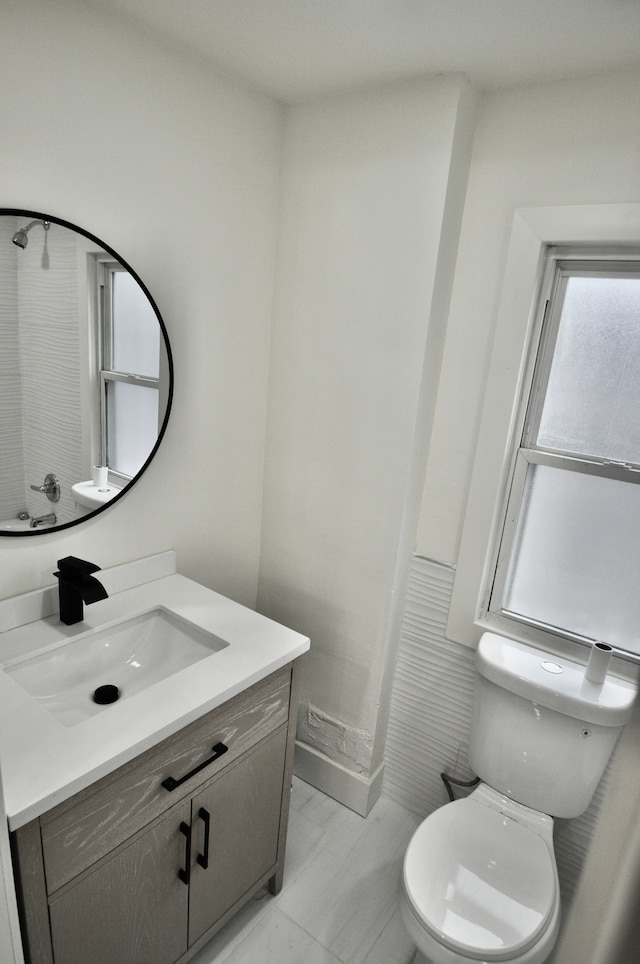 bathroom featuring toilet, vanity, and marble look tile flooring