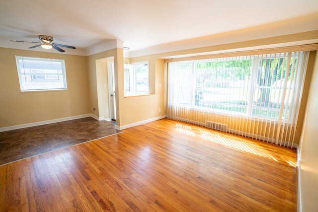 spare room with baseboards, wood finished floors, and a ceiling fan