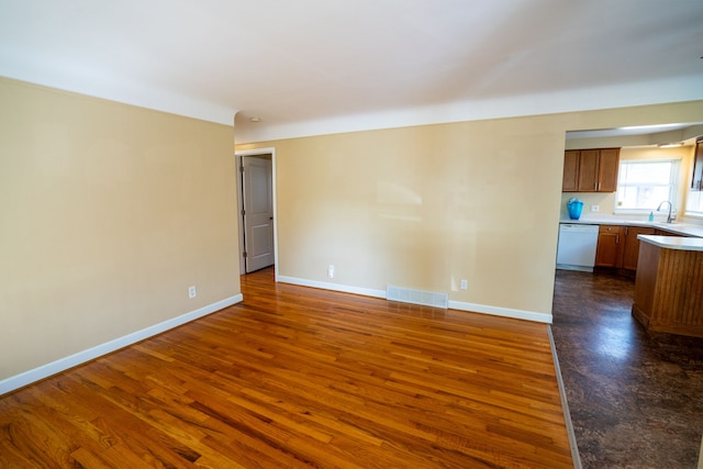 empty room featuring dark wood finished floors, baseboards, and a sink