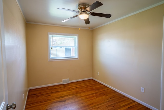 spare room with ornamental molding, wood finished floors, a ceiling fan, and baseboards