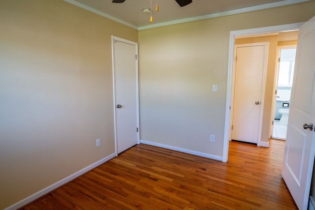 unfurnished bedroom with wood finished floors, baseboards, crown molding, and a ceiling fan