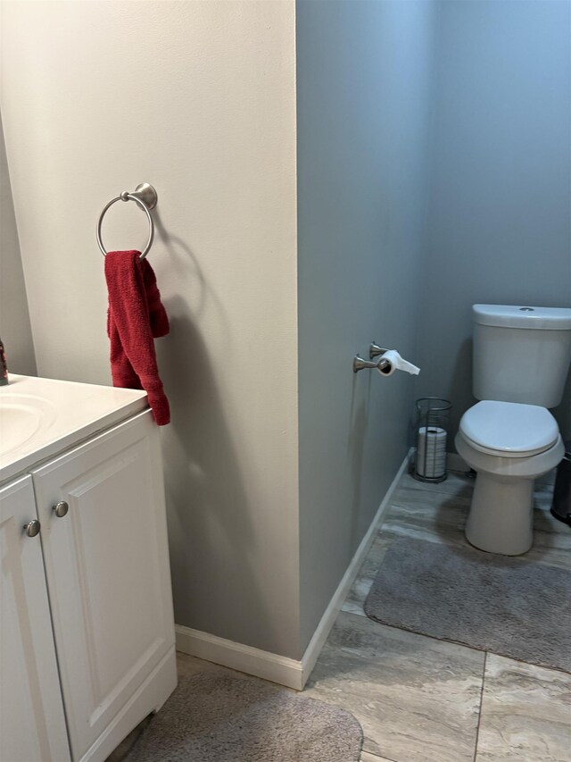 bathroom featuring toilet, baseboards, vanity, and wood finished floors