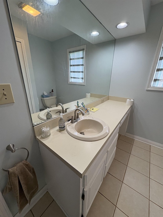bathroom featuring baseboards, tile patterned floors, vanity, and toilet
