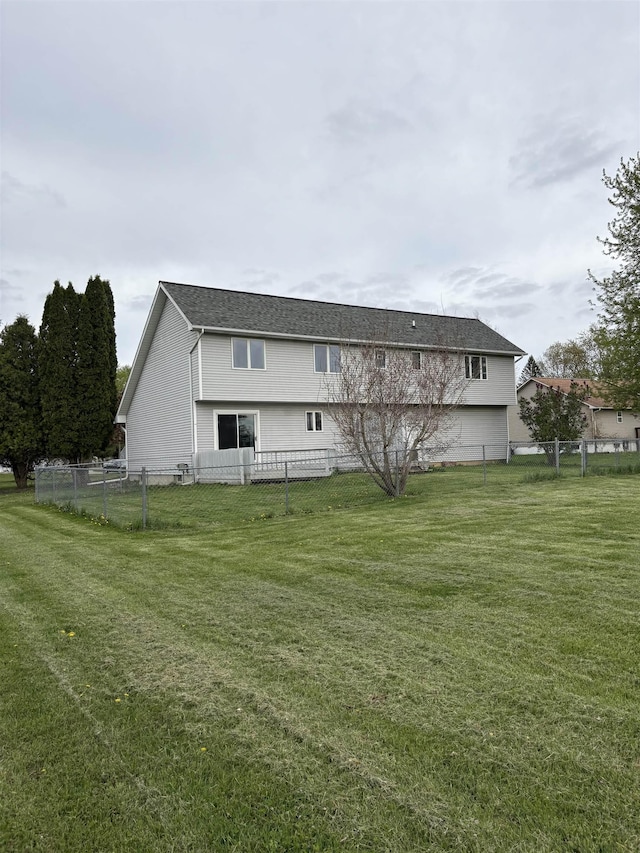 rear view of house featuring a yard and fence