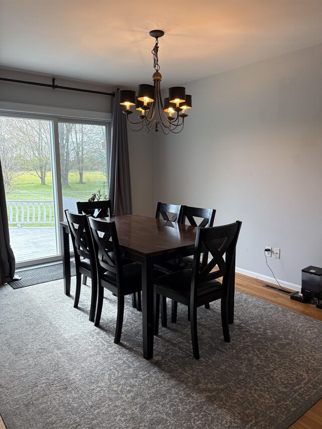dining space with visible vents, wood finished floors, baseboards, and a notable chandelier