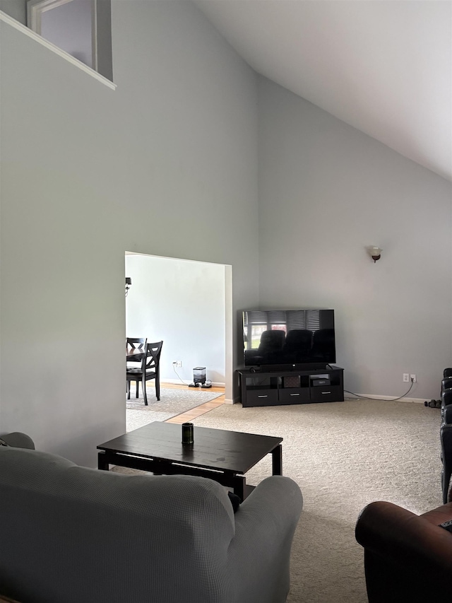 living area featuring baseboards, high vaulted ceiling, and carpet