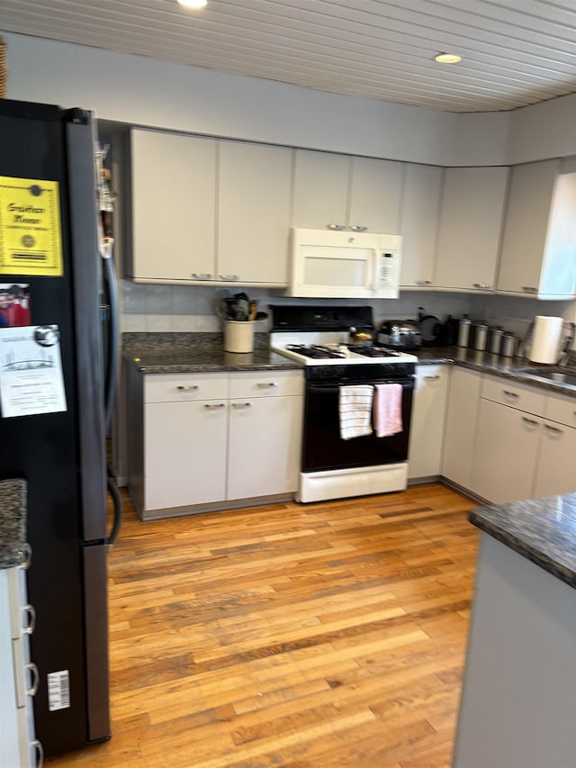 3470 Seymour Rd, Swartz Creek, MI 48473 - kitchen featuring white microwave, freestanding refrigerator, electric range, light wood-style flooring, and dark countertops