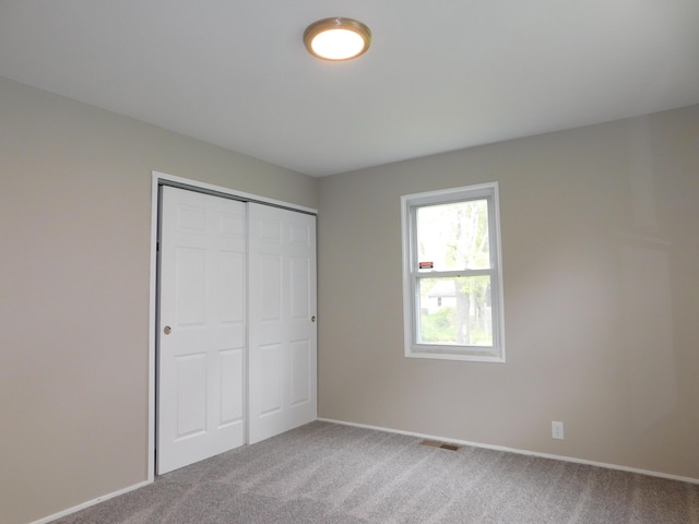 unfurnished bedroom featuring carpet flooring, a closet, visible vents, and baseboards