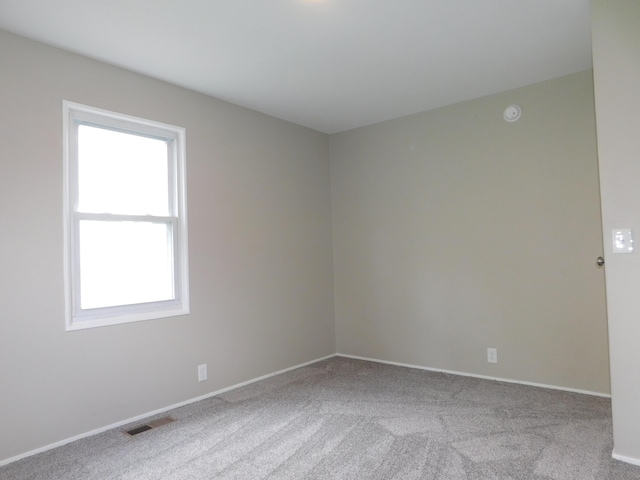 carpeted empty room with visible vents and baseboards