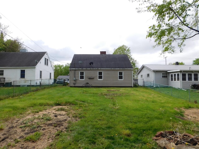 rear view of house featuring a fenced backyard, a chimney, and a lawn