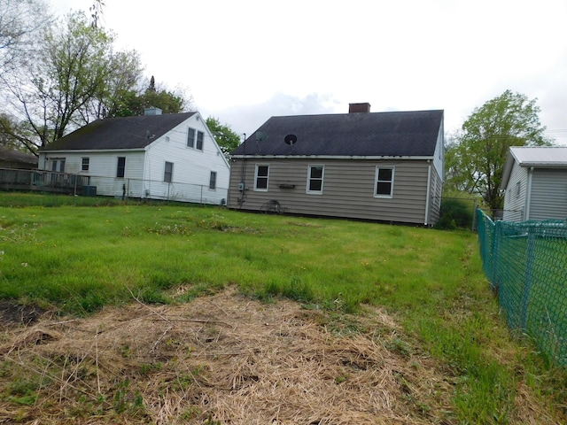 rear view of property featuring a chimney and fence