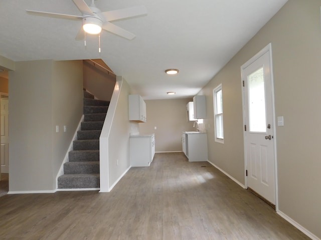 entrance foyer featuring stairs, baseboards, a ceiling fan, and wood finished floors