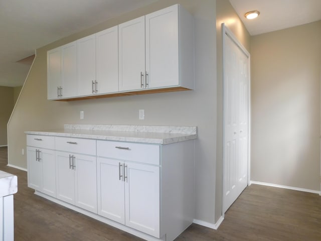 kitchen featuring white cabinets, light countertops, dark wood finished floors, and baseboards