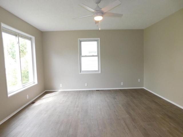 empty room featuring a ceiling fan, baseboards, plenty of natural light, and wood finished floors