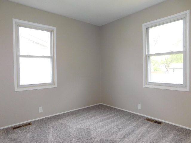 spare room featuring carpet flooring, visible vents, and baseboards