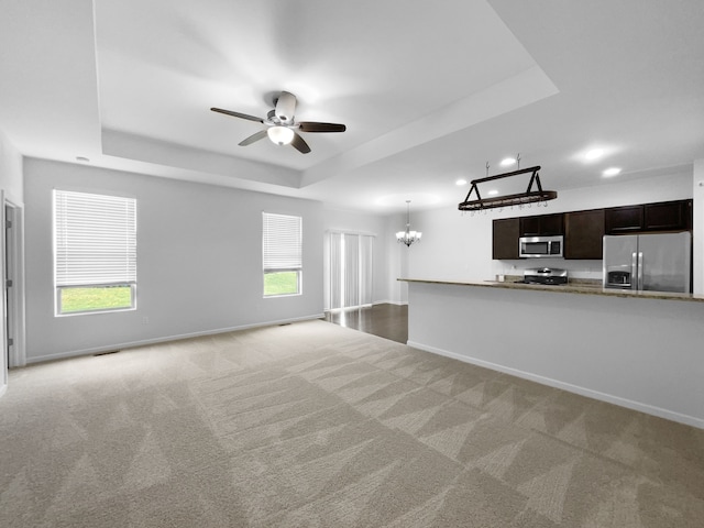 8351 Ardmoor Dr, Ypsilanti, MI 48198 - unfurnished living room with baseboards, a raised ceiling, light carpet, and ceiling fan with notable chandelier