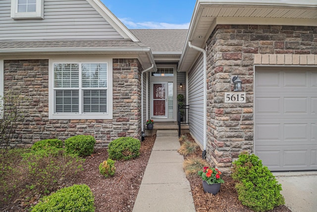 doorway to property with roof with shingles, an attached garage, and stone siding