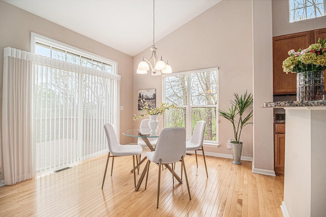 dining area featuring high vaulted ceiling, visible vents, a notable chandelier, baseboards, and light wood-style floors