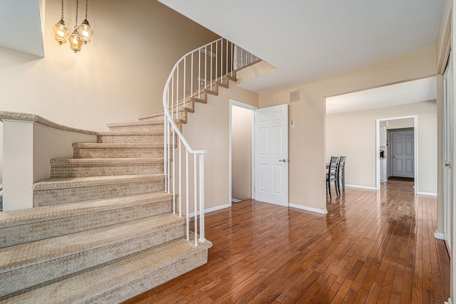 stairway with visible vents, baseboards, and wood-type flooring