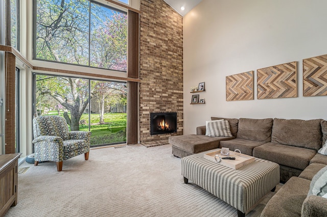 living room featuring light colored carpet, a brick fireplace, and a high ceiling