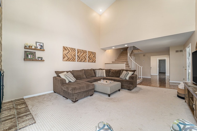 living room with baseboards, stairway, visible vents, and a towering ceiling