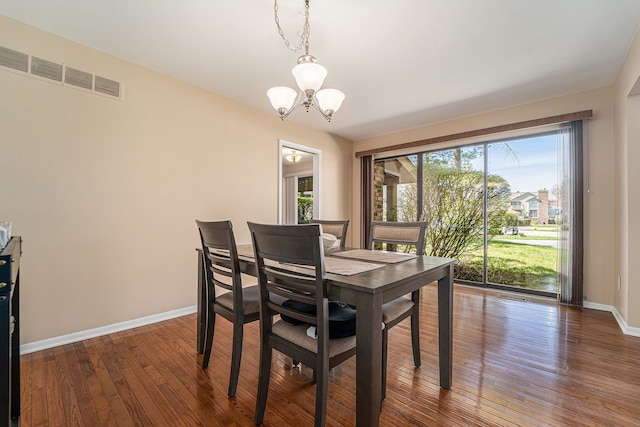 dining area featuring baseboards, a chandelier, visible vents, and dark wood-style floors