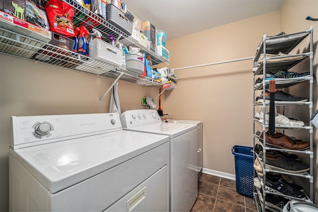 clothes washing area with laundry area, independent washer and dryer, dark tile patterned flooring, and baseboards