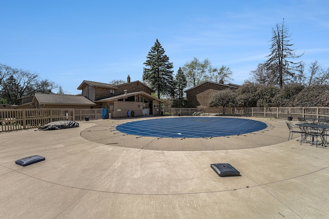 pool with a patio area and fence