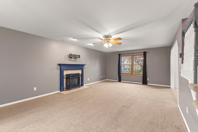 unfurnished living room with carpet flooring, baseboards, a fireplace with flush hearth, and a ceiling fan