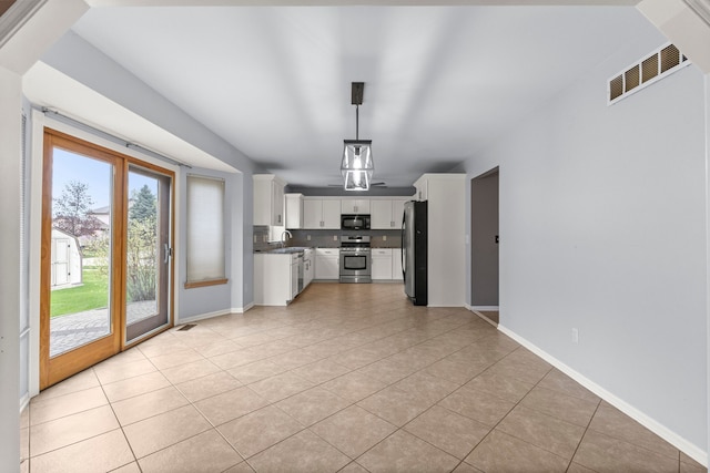 interior space with light tile patterned floors, visible vents, a sink, white cabinets, and appliances with stainless steel finishes
