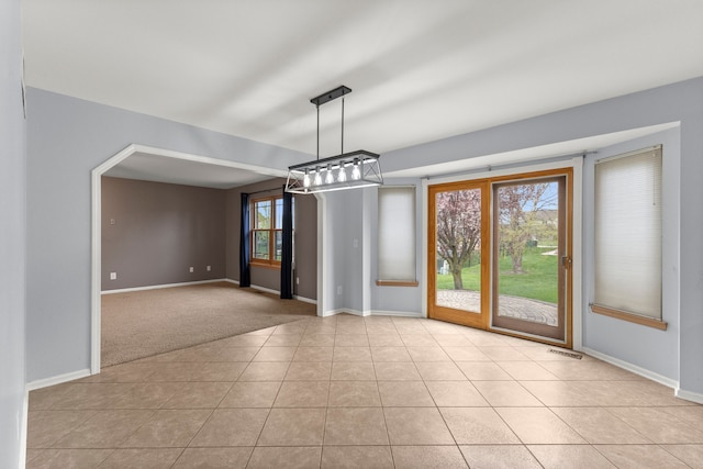 unfurnished dining area with baseboards, tile patterned floors, visible vents, and carpet