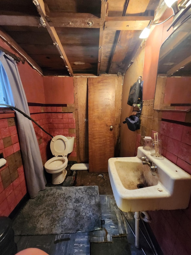 bathroom with tile walls, toilet, and a sink