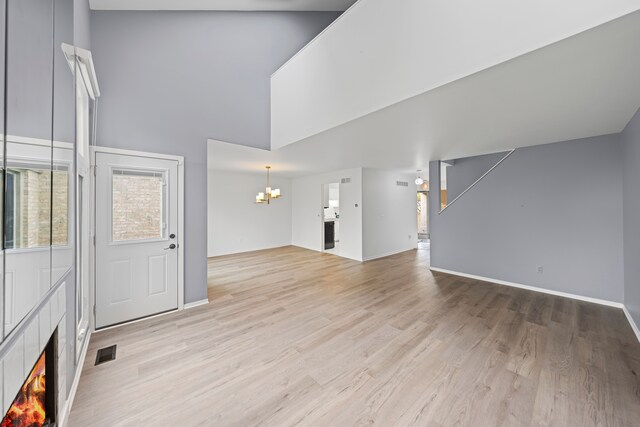 29513 Sierra Pointe Cir, Farmington Hills, MI 48331 - unfurnished living room with a chandelier, a high ceiling, light wood-style floors, a lit fireplace, and baseboards