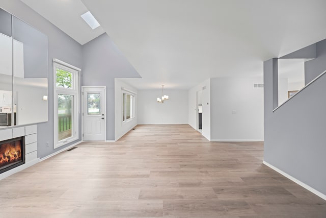 29513 Sierra Pointe Cir, Farmington Hills, MI 48331 - unfurnished living room featuring a chandelier, a tile fireplace, light wood-type flooring, baseboards, and high vaulted ceiling
