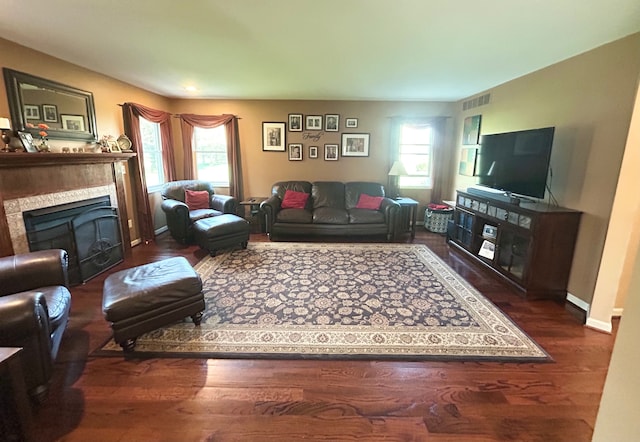 living area with a fireplace, baseboards, visible vents, and wood finished floors