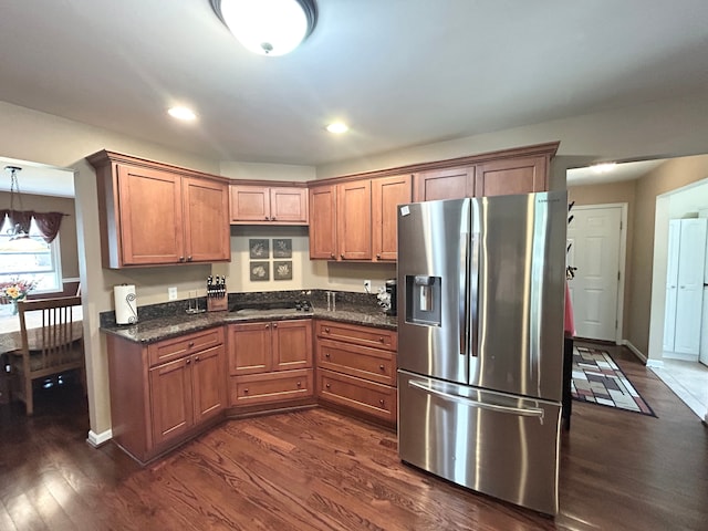 kitchen with brown cabinetry, stainless steel fridge, and dark wood-type flooring