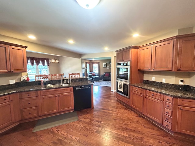 kitchen featuring a peninsula, a sink, stainless steel double oven, dishwasher, and dark wood-style floors