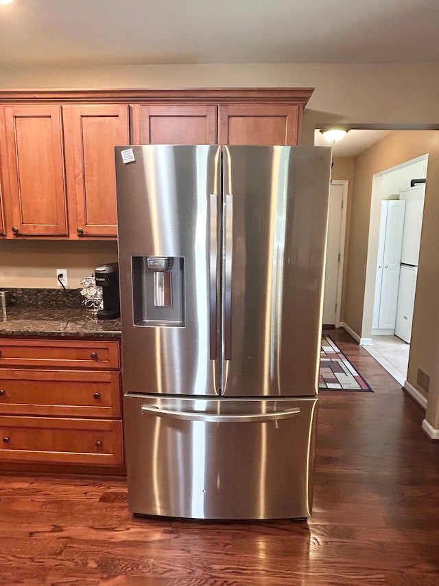 kitchen featuring baseboards, brown cabinets, stainless steel fridge, and dark wood-type flooring