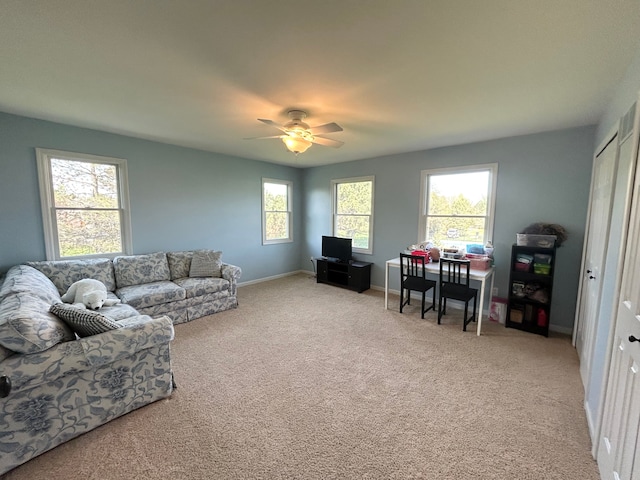 living area featuring carpet flooring, baseboards, and a ceiling fan