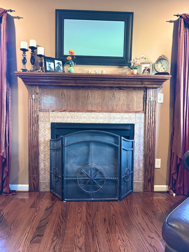 interior details with baseboards, a tiled fireplace, and wood finished floors