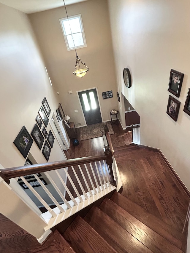stairway with baseboards, a high ceiling, and wood finished floors