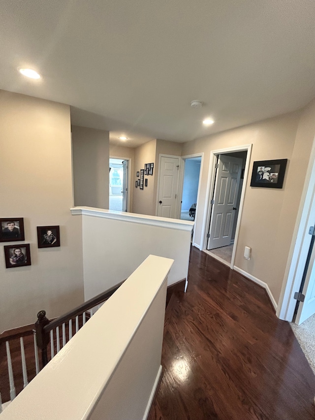 corridor with dark wood-style flooring, baseboards, an upstairs landing, and recessed lighting