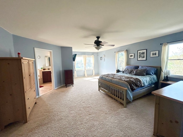 bedroom featuring a ceiling fan, light carpet, and connected bathroom