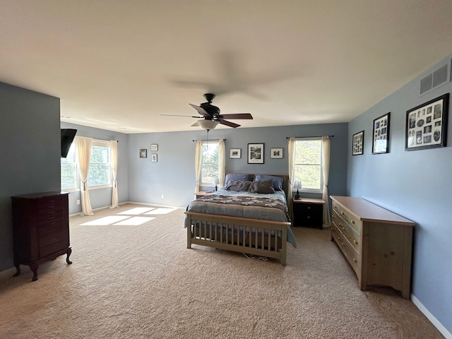 bedroom with light colored carpet, visible vents, and multiple windows