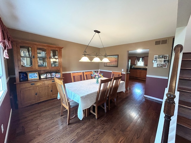 dining space featuring dark wood-style flooring, stairway, and visible vents